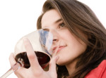 a beautiful woman smell a red glass wine